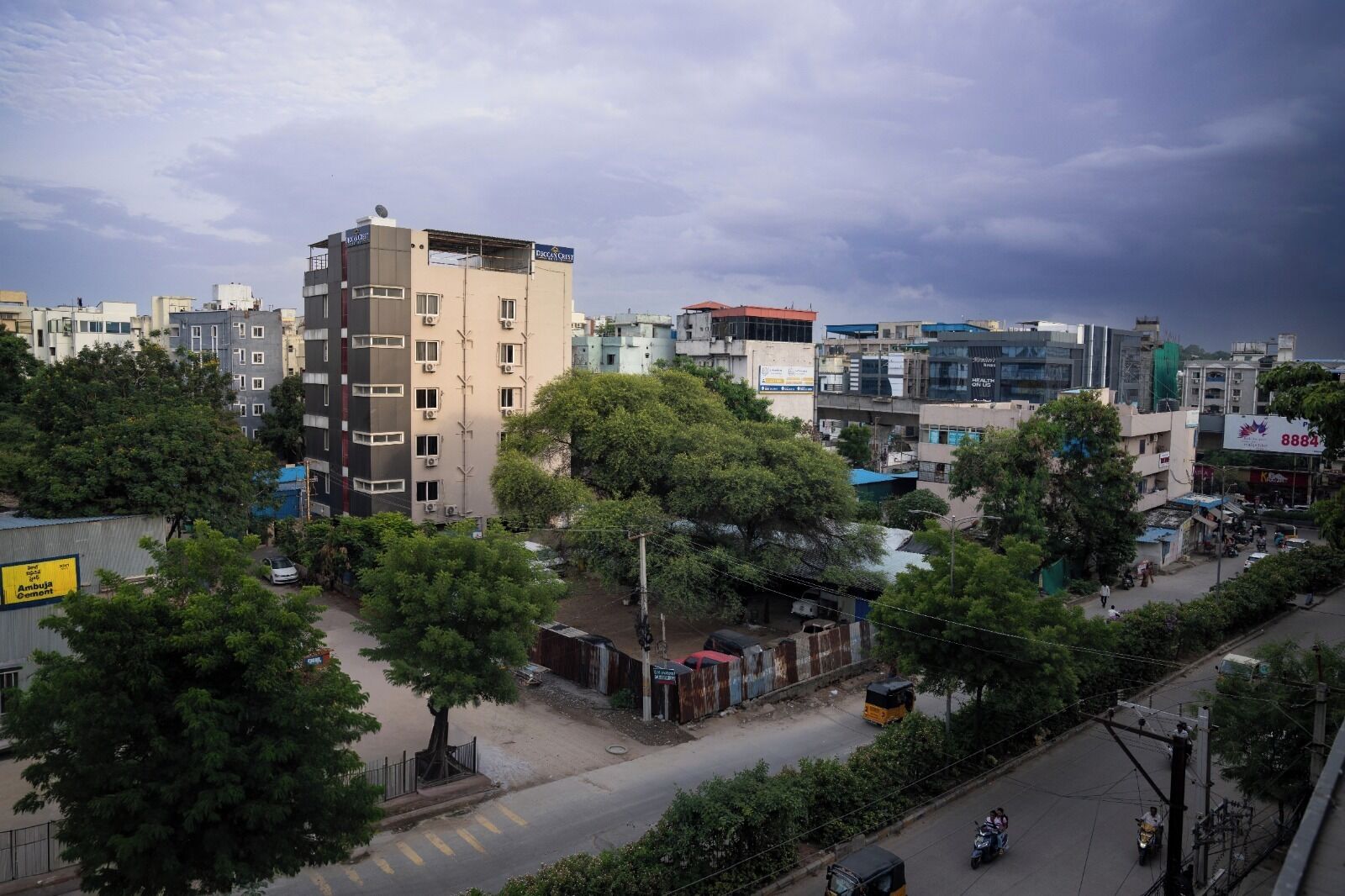 Un paisaje urbano con edificios de varios pisos, una calle con vehículos y árboles.
