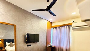 Habitació d'hotel moderna amb un llit gran, un ventilador de sostre, una televisió de pantalla plana i un mirall gran.