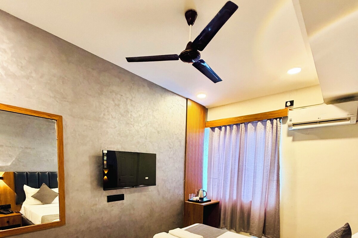 Een moderne hotelkamer met een groot bed, een plafondventilator, een flatscreen televisie en een grote spiegel.