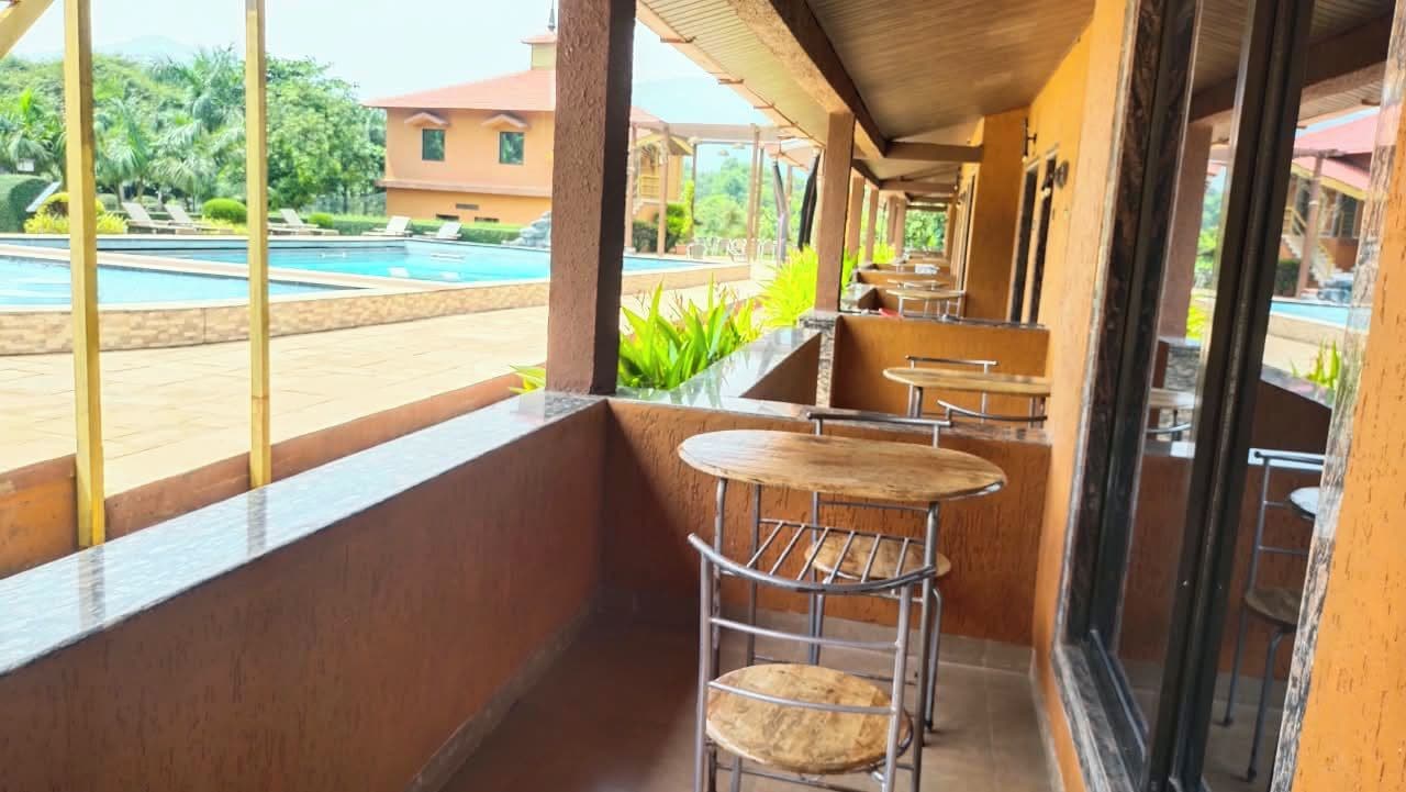 Un espace extérieur abrité avec vue sur la piscine, comprenant des tables et des chaises.