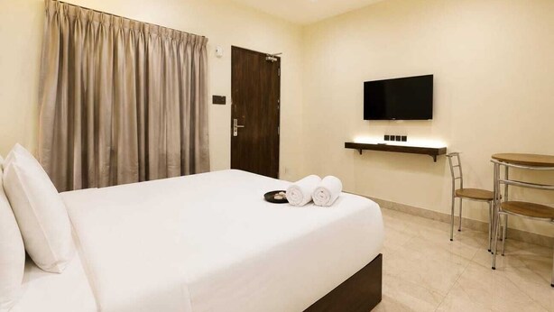 Una habitación de hotel con cama, televisión, una mesita y una silla.