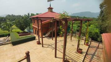 A gazebo with a red roof, surrounded by potted plants and a well-maintained lawn.