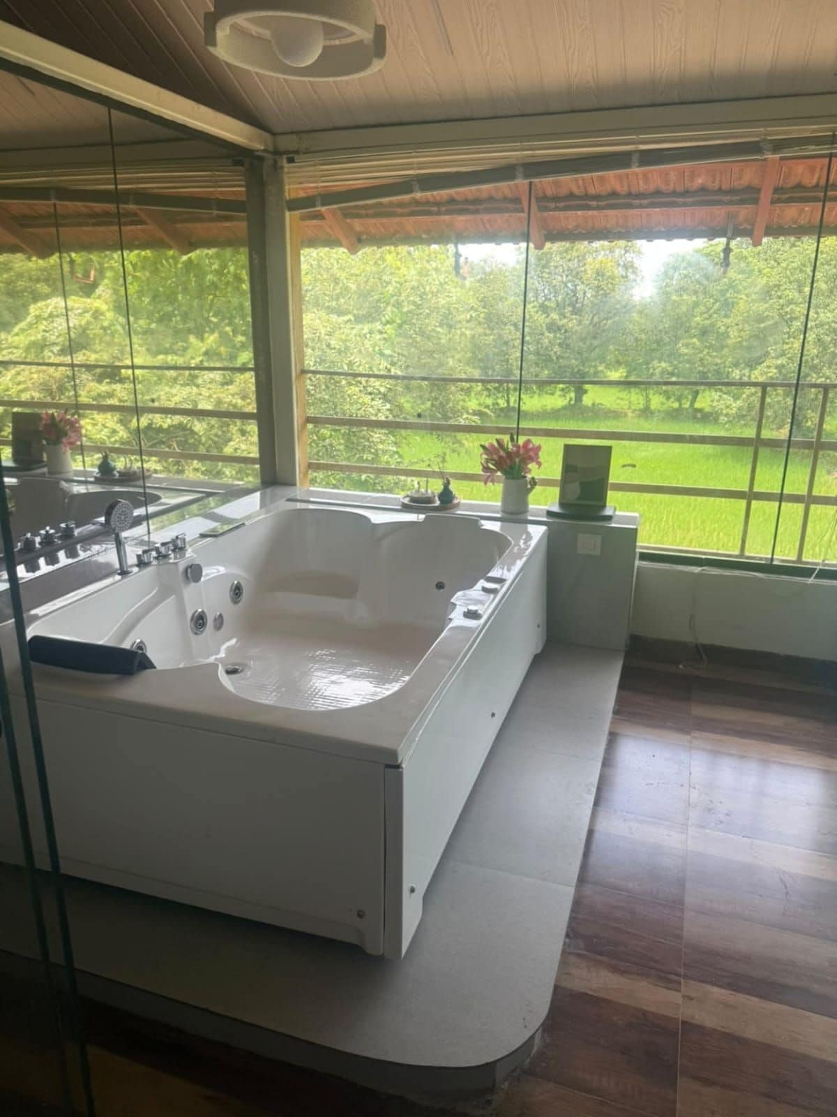 Un baño moderno con una bañera grande, una ducha y un ventanal con vistas a un jardín exuberante.