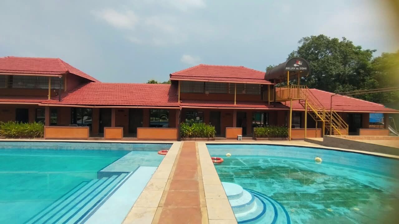Un hotel con piscina, un edificio de techo rojo y un letrero que indica una zona de relajación.
