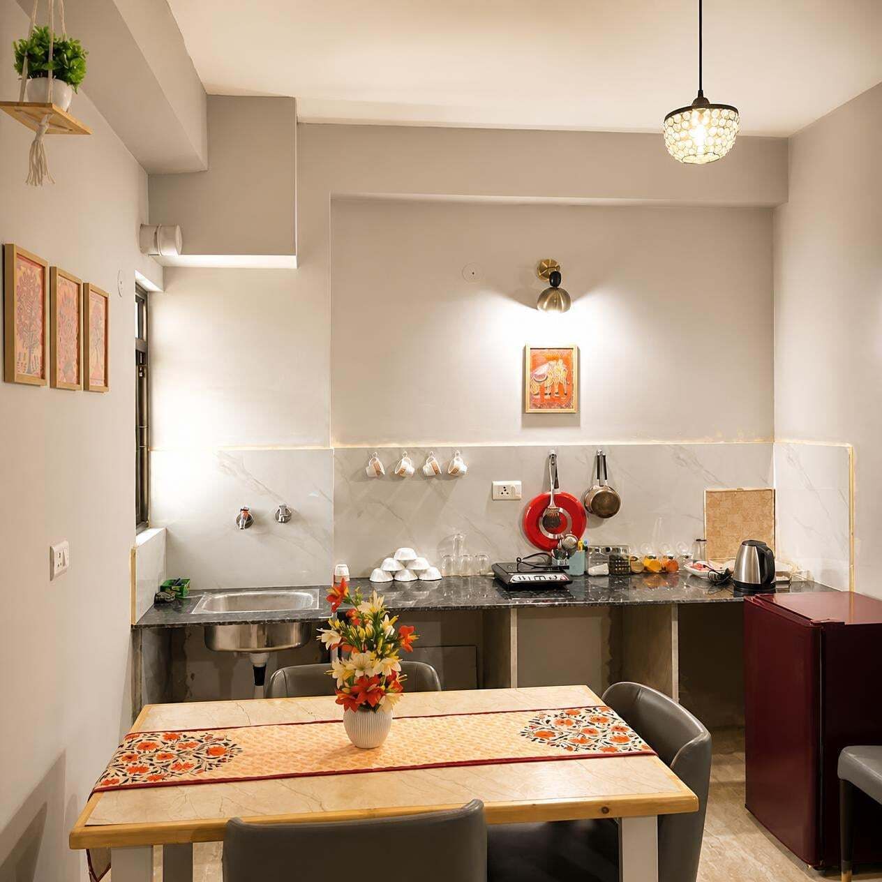 A modern kitchen with a dining area, featuring a marble backsplash, stainless steel appliances, and a hanging light fixture.