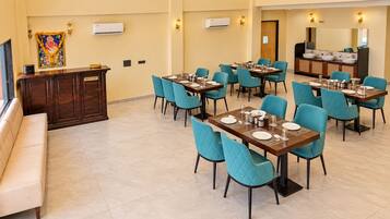 Un comedor de hotel con varias mesas y sillas, una recepción y un cartel indicador.