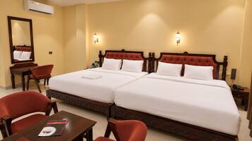 A hotel room with two beds, a desk, chairs, and a mirror.