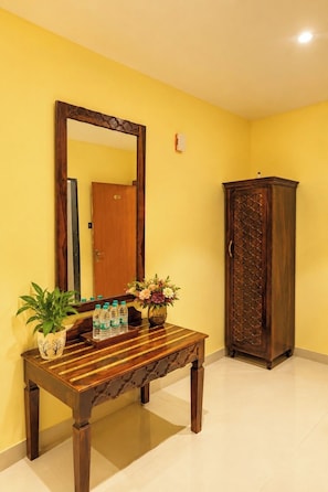 Una habitación con un banco de madera, un espejo, un armario y una planta en maceta.
