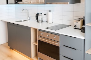 A modern kitchen with a built-in dishwasher, oven, and a coffee maker on the countertop. - Oceanfront Bliss with Breathtaking Views (Cape Town)