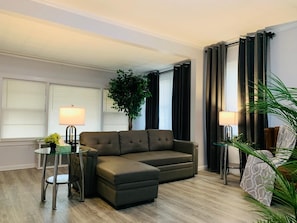 Una sala de estar moderna con un sofá modular, una mesa de centro de vidrio y dos lámparas.
