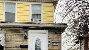 A house with a white front door, stone facade, and a number '125' sign.
