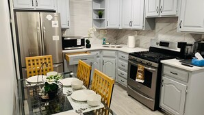 A modern kitchen with white cabinetry, stainless steel appliances, and a dining area with a glass table and chairs.