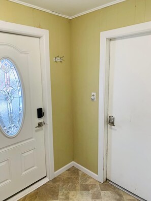 A corner of a room with a white door, a glass door with a decorative design, and a wall with a light yellow color.