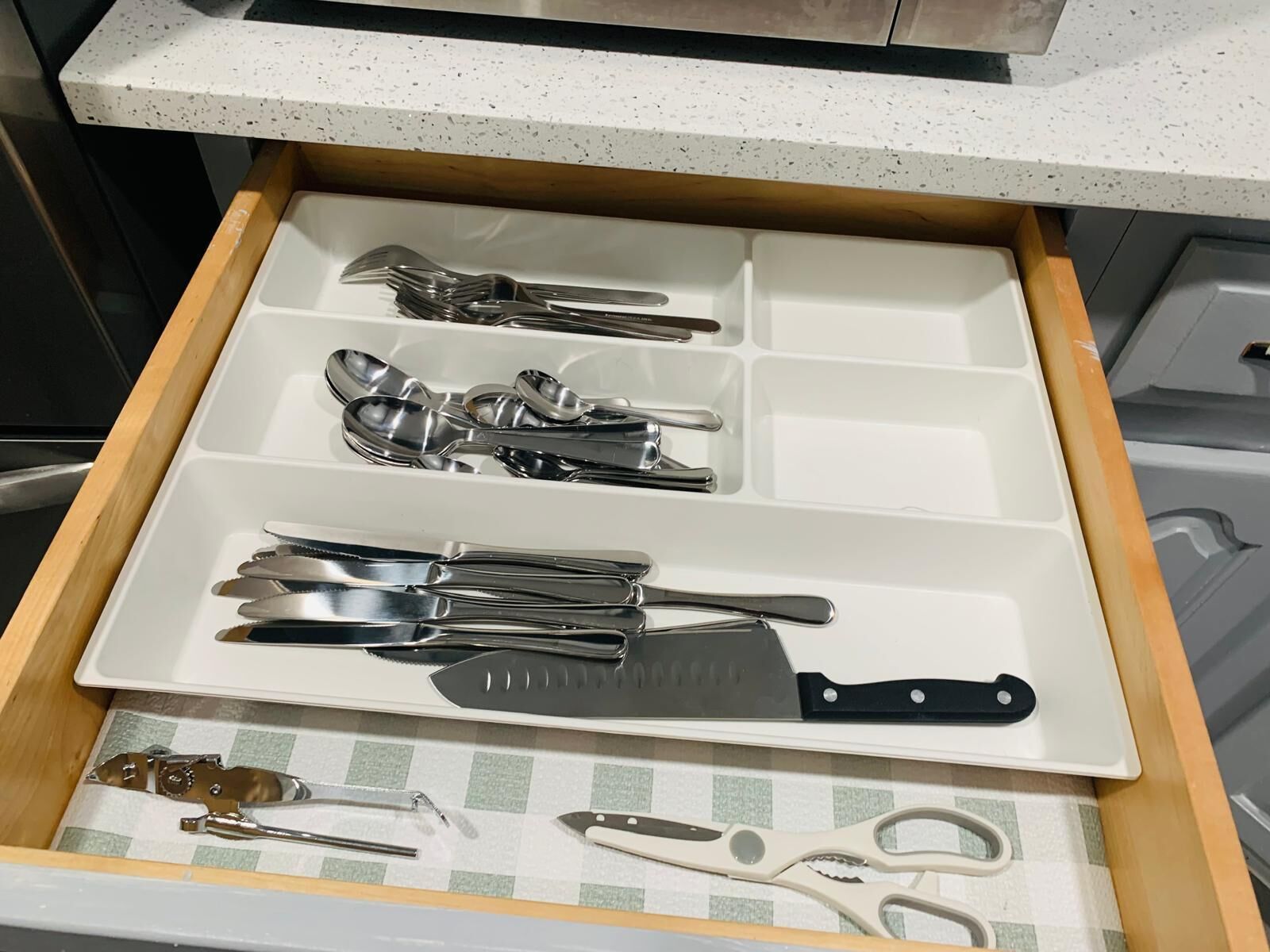 Un cajón de cocina con utensilios organizados en compartimentos.