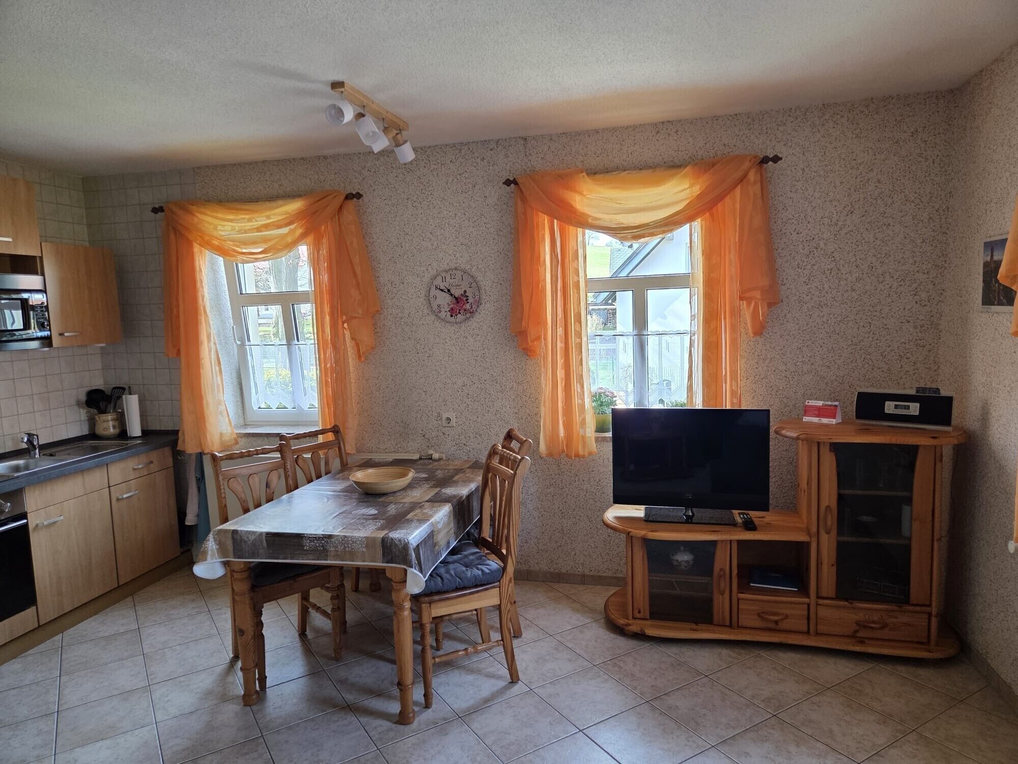 Eine Küche mit Esstisch, Stühlen, Fernseher und Schrank.
