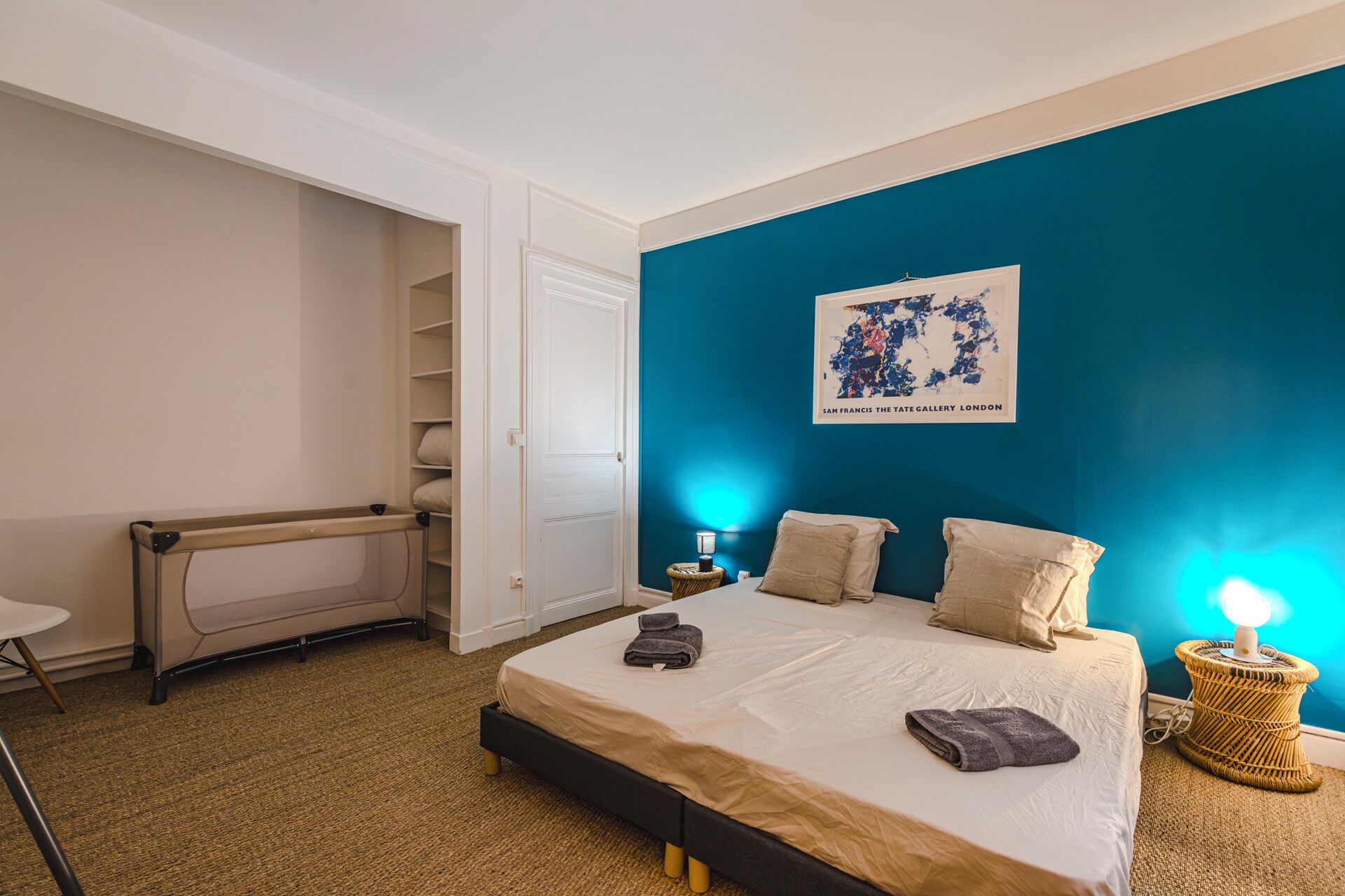 Une chambre à coucher avec un lit, une table de chevet, une lampe, une carte accrochée au mur et une armoire.