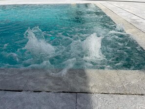 En swimmingpool med klart vatten och en synlig vattenfontän som skapar vågor.