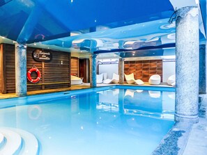 Een binnenzwembad met drijver, een sauna en een receptie.