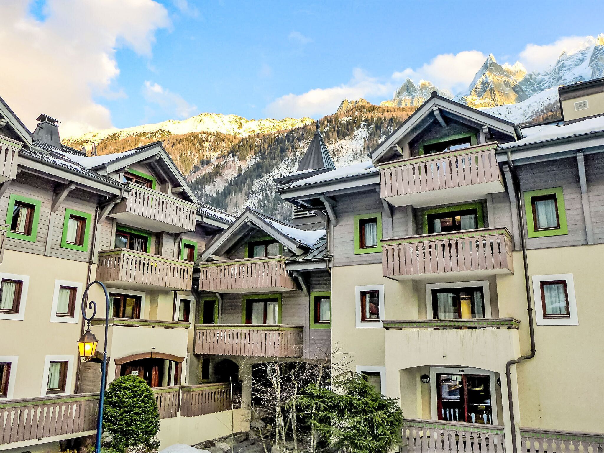 A hotel with multiple balconies, a mountain backdrop, and a clear sky.