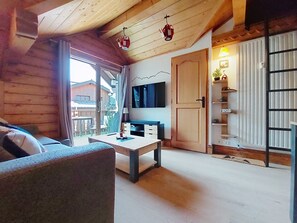 En inredning med träpanel, en soffa, ett bord och en tv som är monterad på väggen.