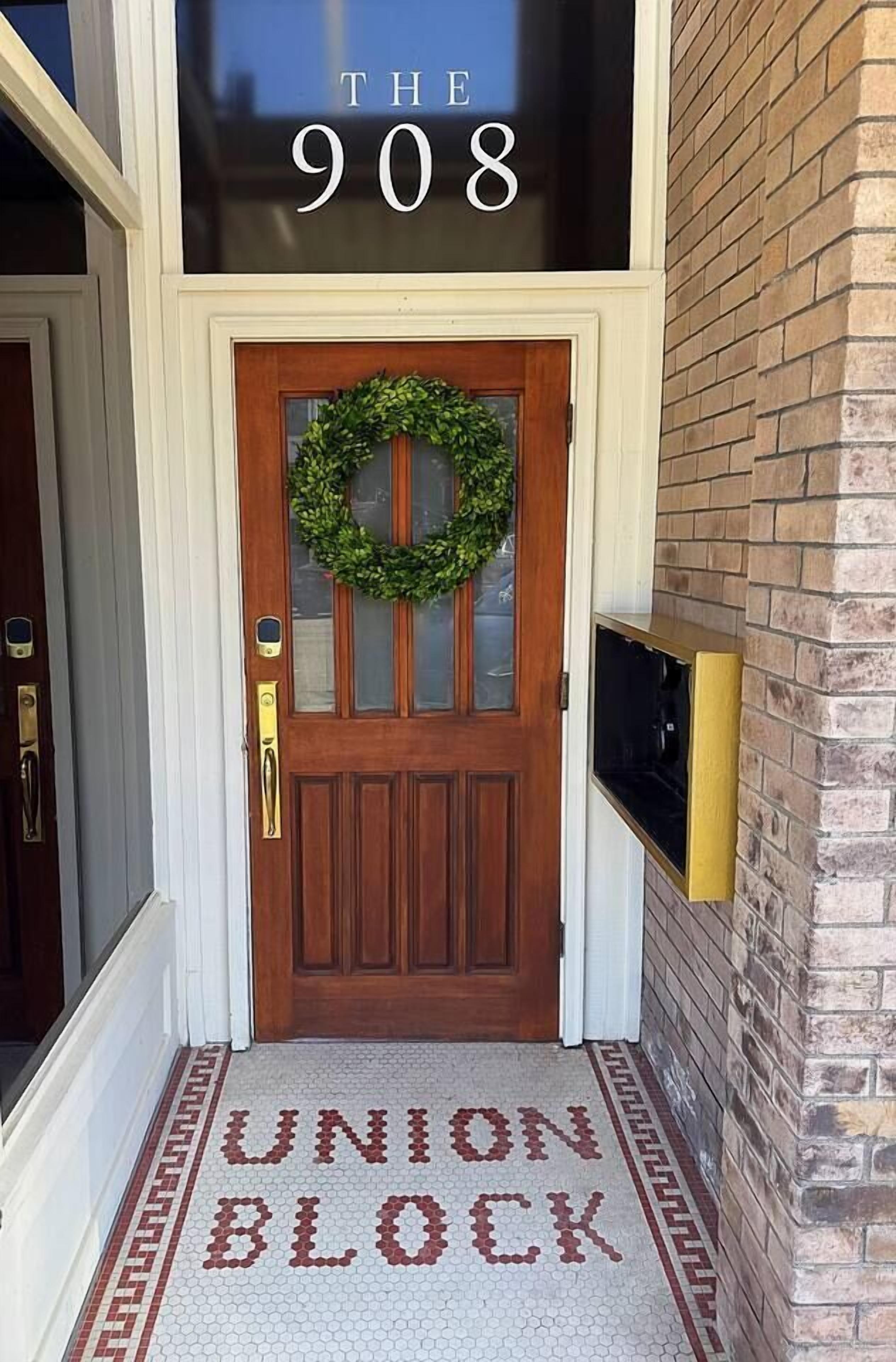 A wooden front door with a wreath, a sign above stating 'THE 908', and a 'UNION BLOCK' sign on the floor.