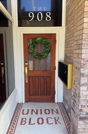 A wooden front door with a wreath, a sign above stating 'THE 908', and a 'UNION BLOCK' sign on the floor. - Historic King Suite | Downtown Snohomish Views (Snohomish)