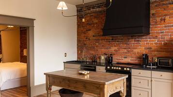 Una cocina funcional con pared de ladrillo, una mesa de madera y electrodomésticos modernos.