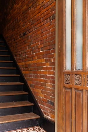 A staircase with a brick wall on one side and a wooden door with glass panels on the other. - Historic King Suite | Downtown Snohomish Views (Snohomish)