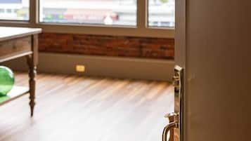 Una habitación con un ventanal grande, suelo de madera y una puerta con un número.