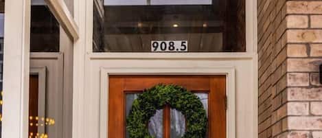 A wooden front door with a wreath, a number '908.5' above it, and a 'UNION BLOCK' mat at the entrance.