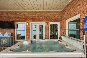 Een zone met een bubbelbad, een bakstenen muur, een televisie en een bord met de openingstijden van het bubbelbad.