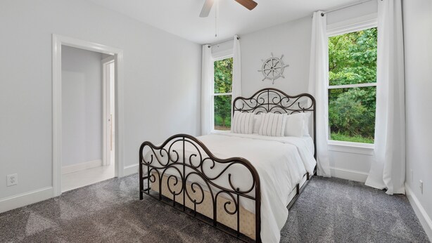 A bedroom with a bed, a ceiling fan, and two windows with curtains. - Lakefront + Private Dock | Hot Tub + Pool Table + Cabana | Point of View (Mooresville)
