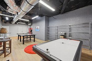 Ein Zimmer mit Tischtennisplatte, Regalen und einem roten Teppich.