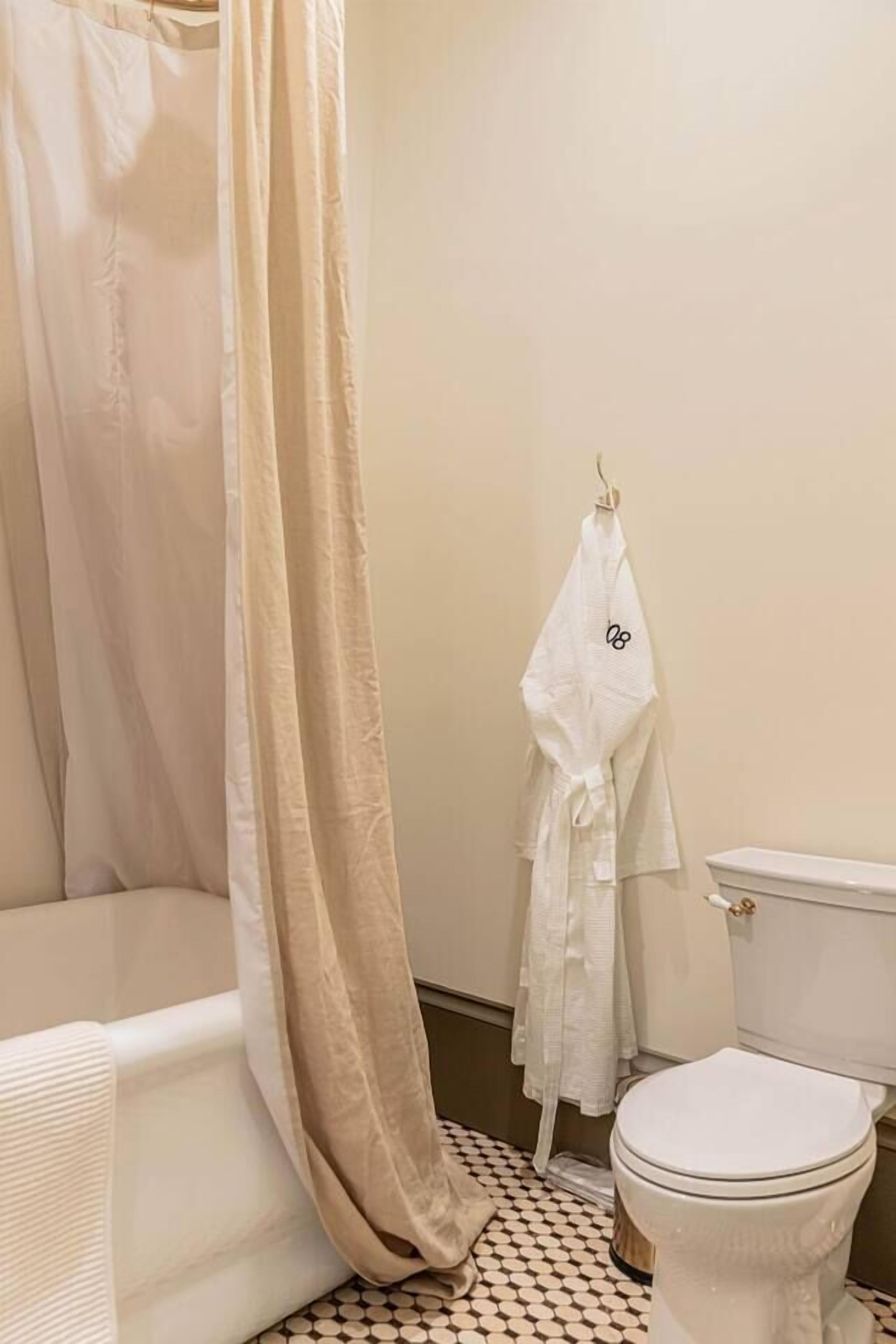 A bathroom with a bathtub, toilet, and a shower curtain.