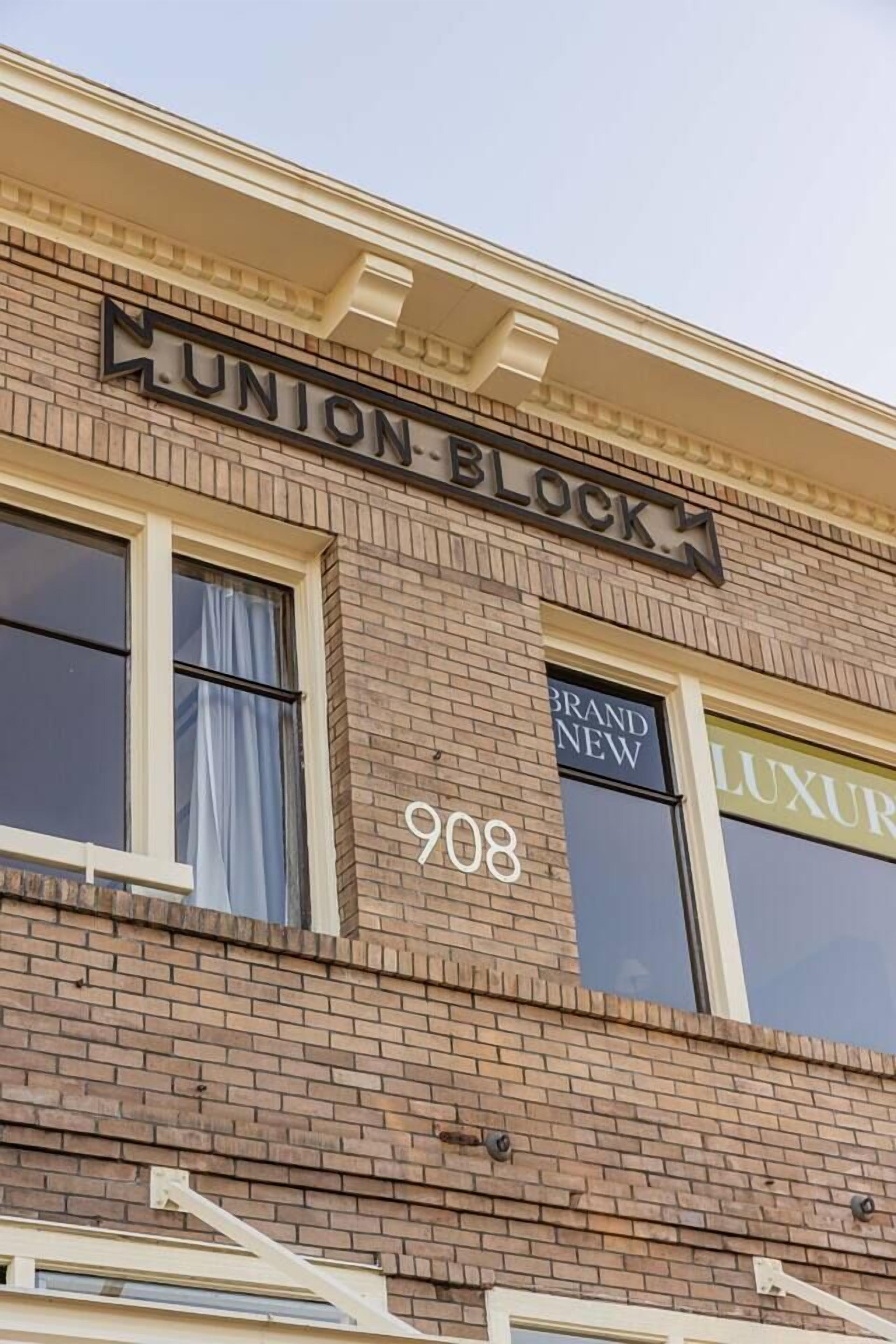 Tiilestä rakennettu rakennus, jossa on kyltti, jossa lukee ”Union Block”, ja ikkunassa on kyltit, joissa lukee ”Uusi” ja ”Ylellinen”.