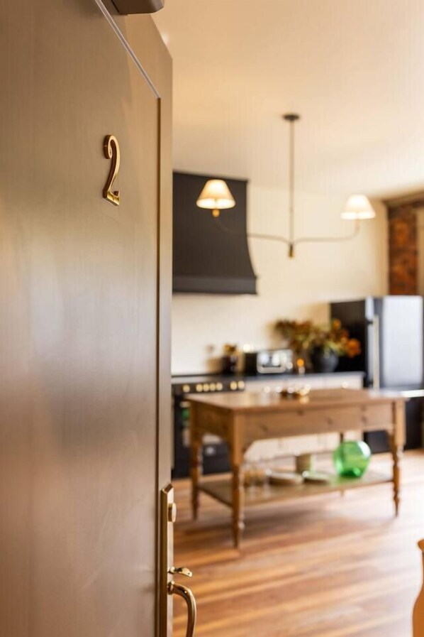 A modern kitchen with wooden flooring, a dining table, and pendant lighting.