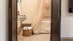 Un couloir menant à une salle de bain équipée d’un rideau de douche, d’un lavabo et d’un porte-serviettes.