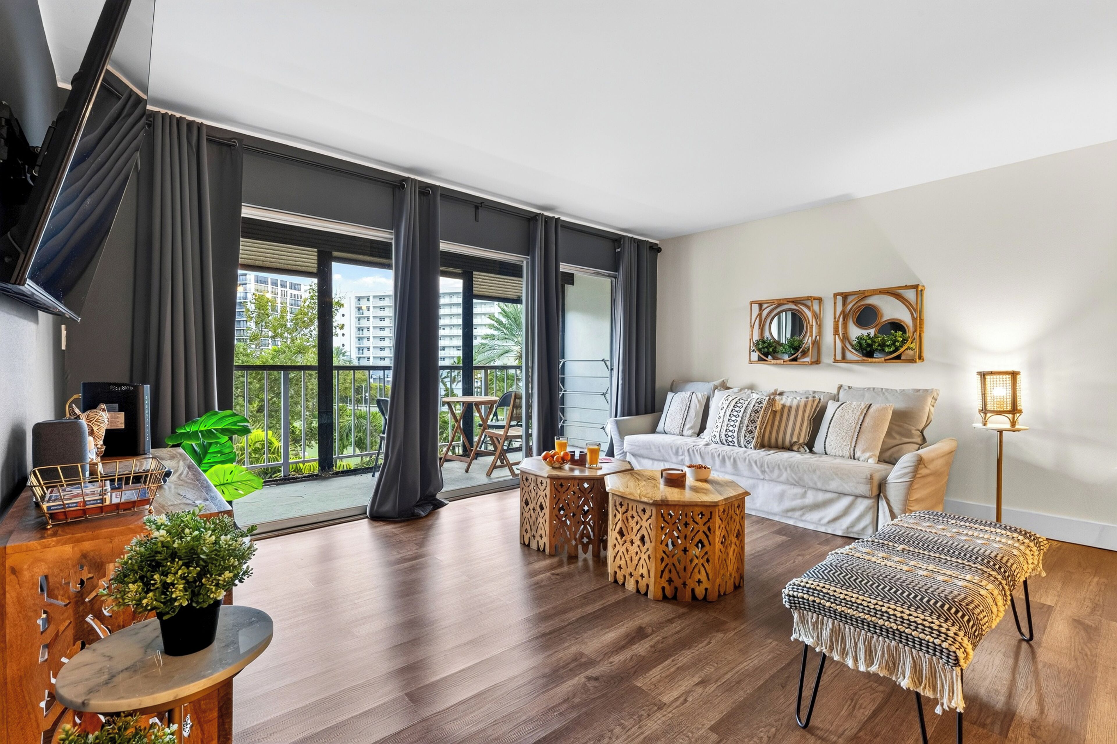 A modern living room with a sofa, coffee table, and a balcony with a view of buildings.
