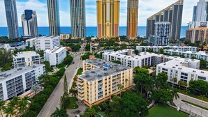 A cityscape with high-rise buildings, a road, and greenery. - Garden Balcony + Pool + Deck | Walk to Beach + Dining | Skyline & Salt (Sunny Isles Beach)