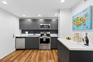 Eine moderne Küche mit grauen Schränken, Edelstahlgeräten, einem Holzboden und einer Karte der Vereinigten Staaten an der Wand.