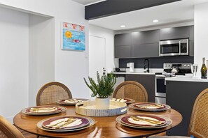 Eine moderne Küche mit Mikrowelle, Backofen und Essbereich mit rundem Tisch für sechs Personen.