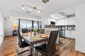 A modern kitchen with white cabinets, a stainless steel dishwasher, and a microwave. - Sunny Isles Condo • Shared Pool + Private Balcony • Near Beaches | Isle Vista (Sunny Isles Beach)