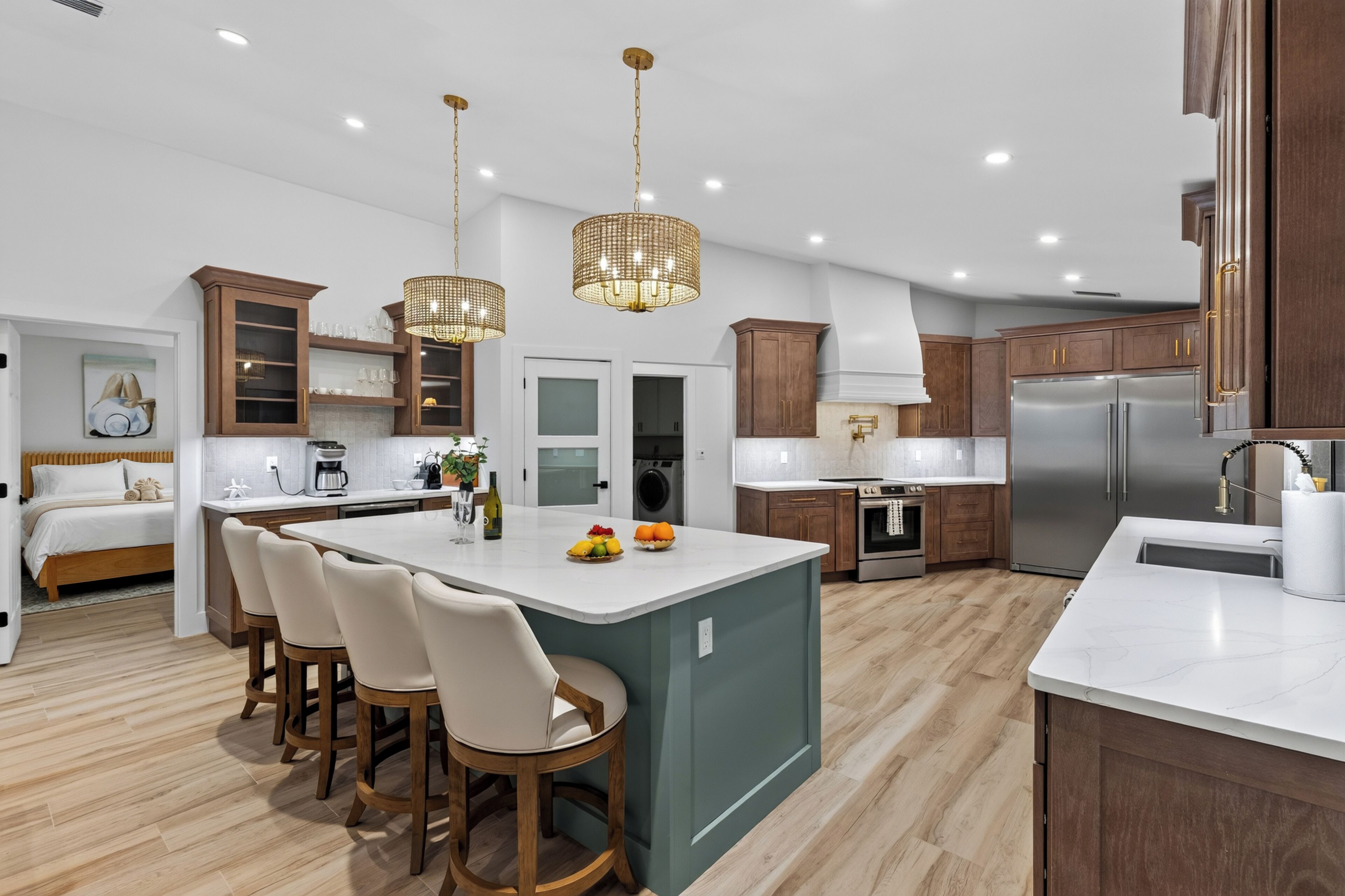 A modern kitchen with a central island, wooden cabinets, and pendant lighting.