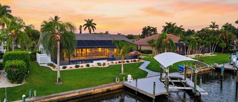 A waterfront property with a swimming pool, dock, and lush landscaping.
