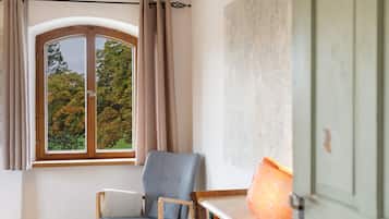 A room with a window, a chair, a table, and a lamp.