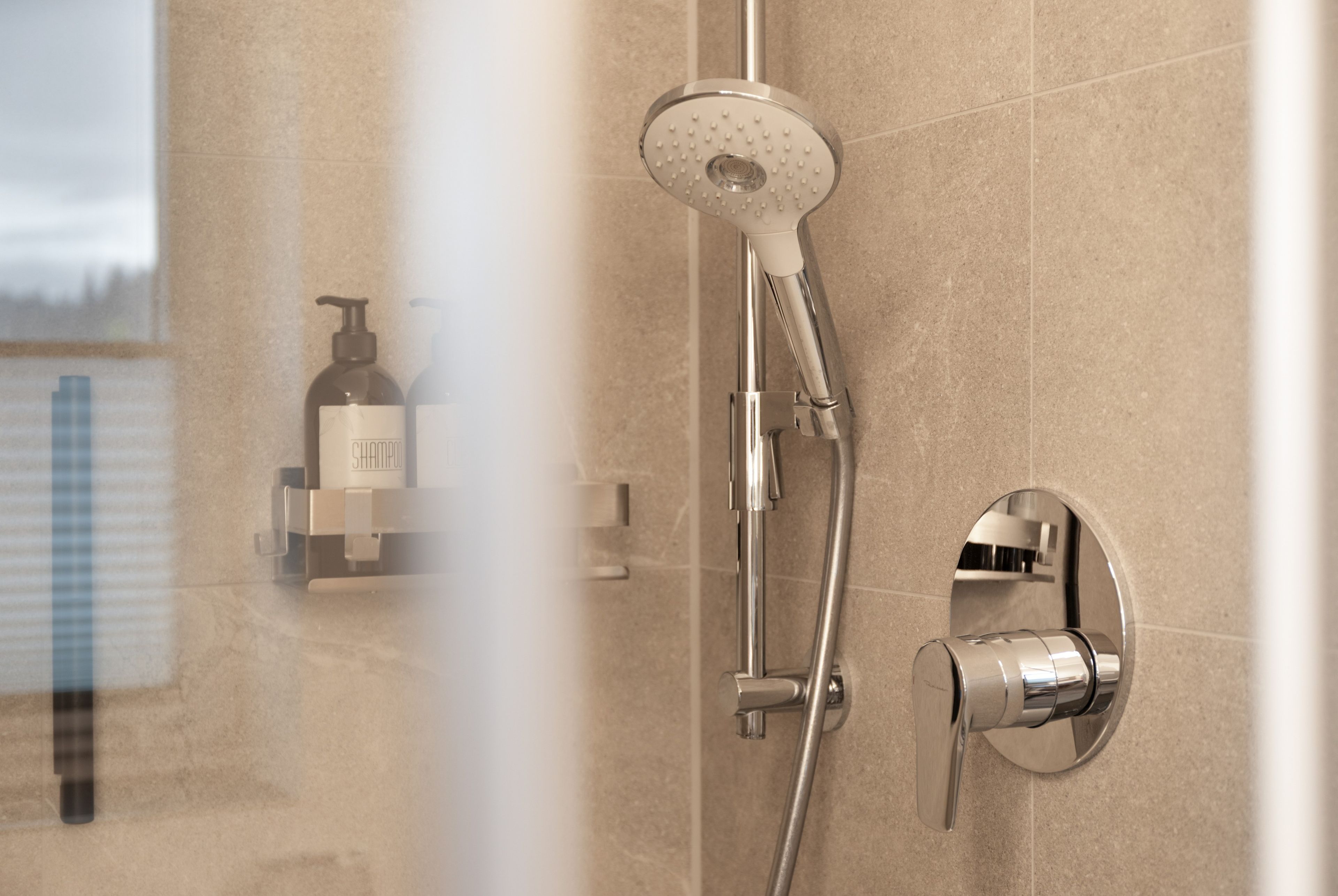 A shower with a handheld showerhead and a wall-mounted control valve.