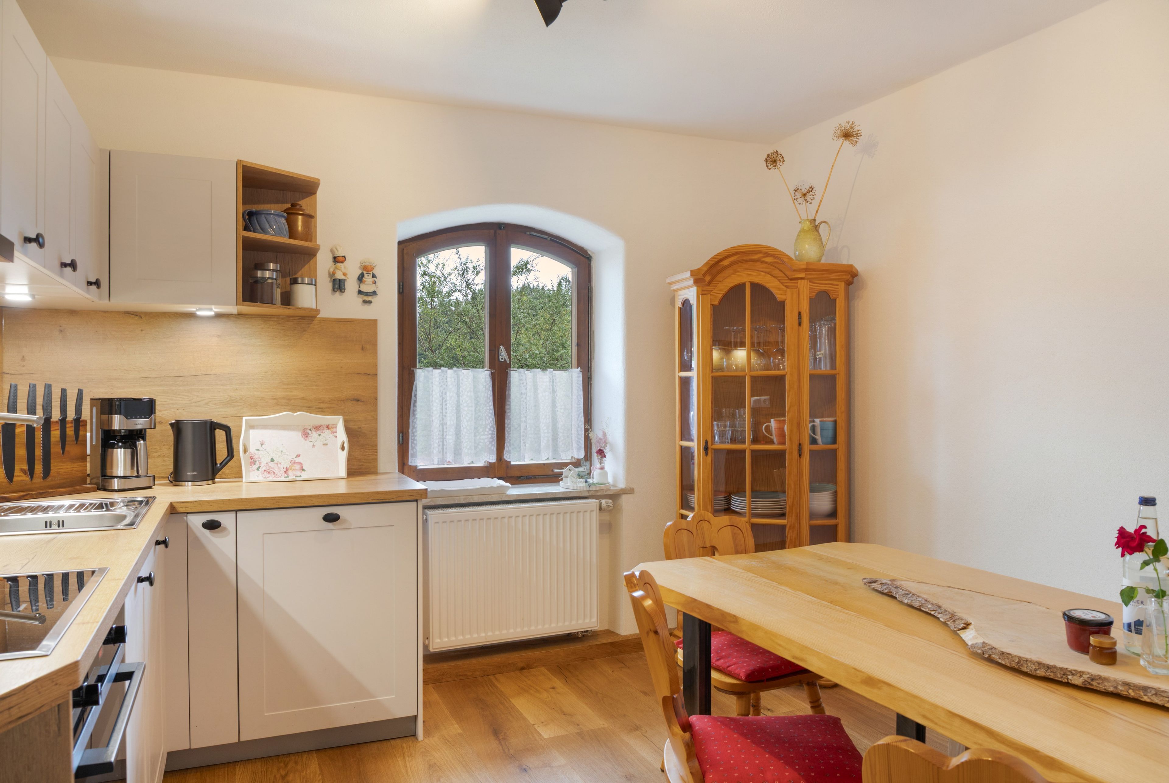 Eine kompakte Küche mit Geschirrspüler, Kaffeemaschine und einem Essbereich mit Holztisch und Stühlen.