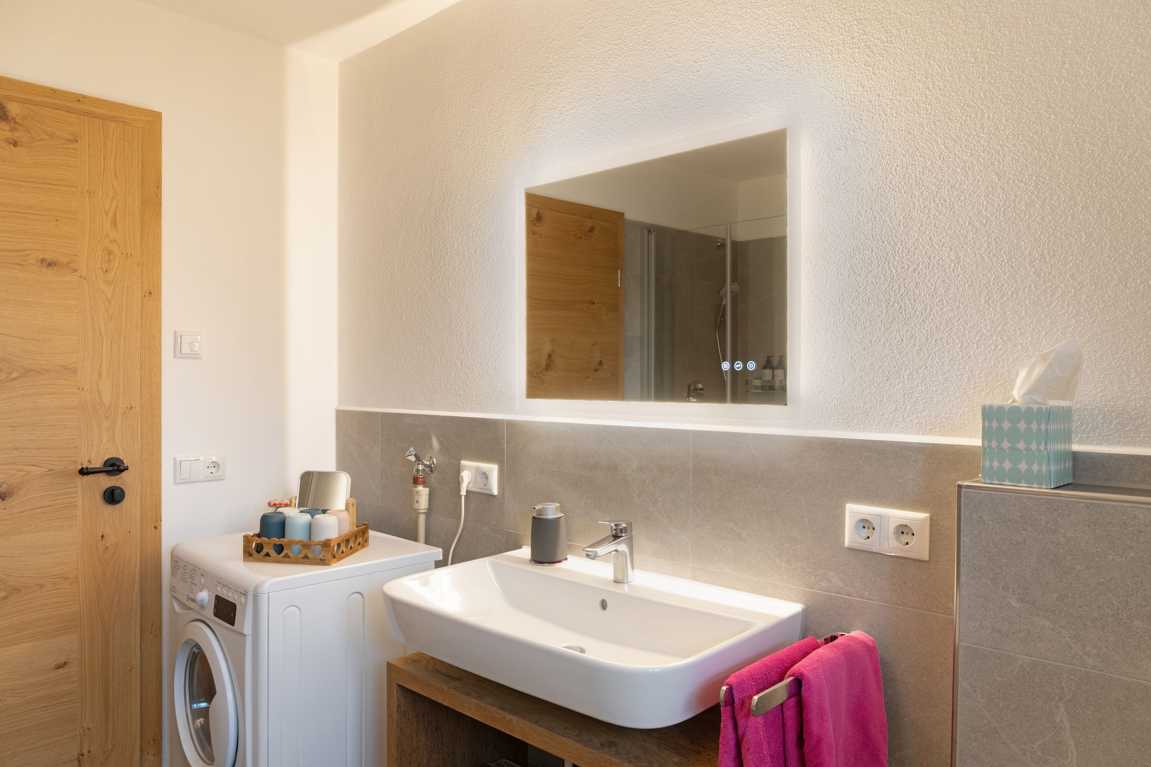 Ein modernes Badezimmer mit Waschmaschine, Waschbecken und Spiegel.