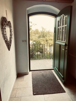 An interior hallway leading to a balcony with a view of trees and a metal fence. - Farmhouse 'Niederbleick' with Mountain View, Shared Garden and Wi-Fi (Wildsteig)