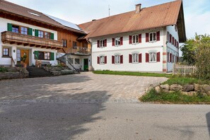 A traditional European-style building with a paved courtyard, wooden balconies, and red shutters. - Farmhouse 'Niederbleick' with Mountain View, Shared Garden and Wi-Fi (Wildsteig)